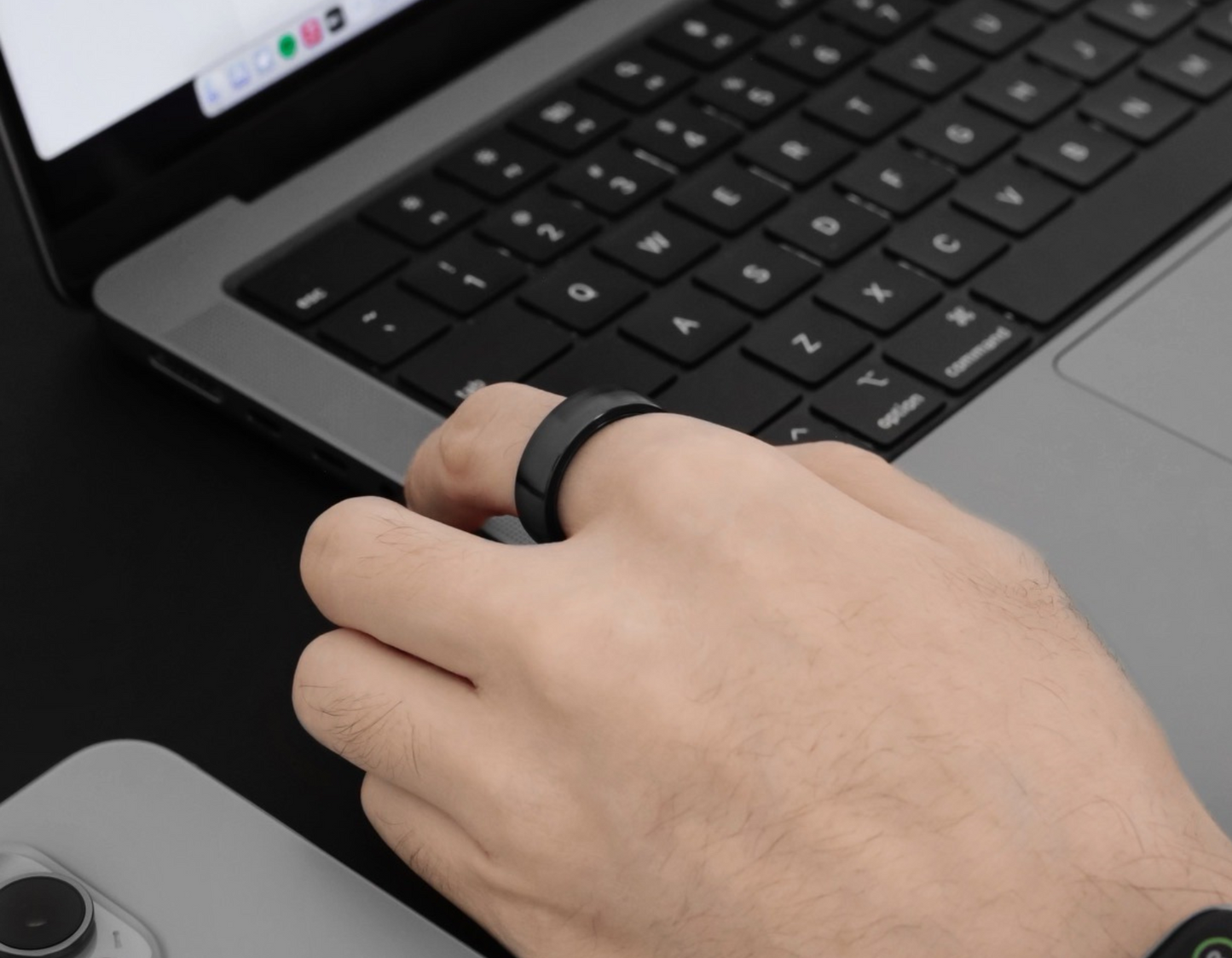 A hand wearing the Polar Ring by a laptop working.