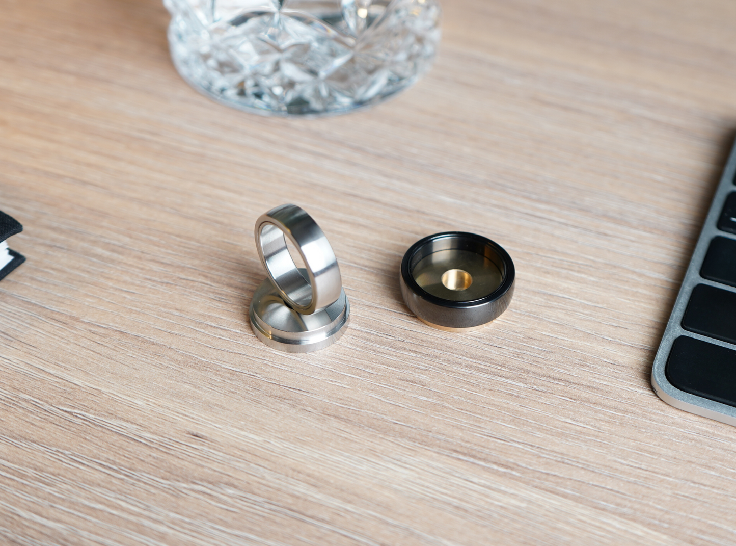 A steel and a black Polar Ring sitting on steel and gold desk stands.